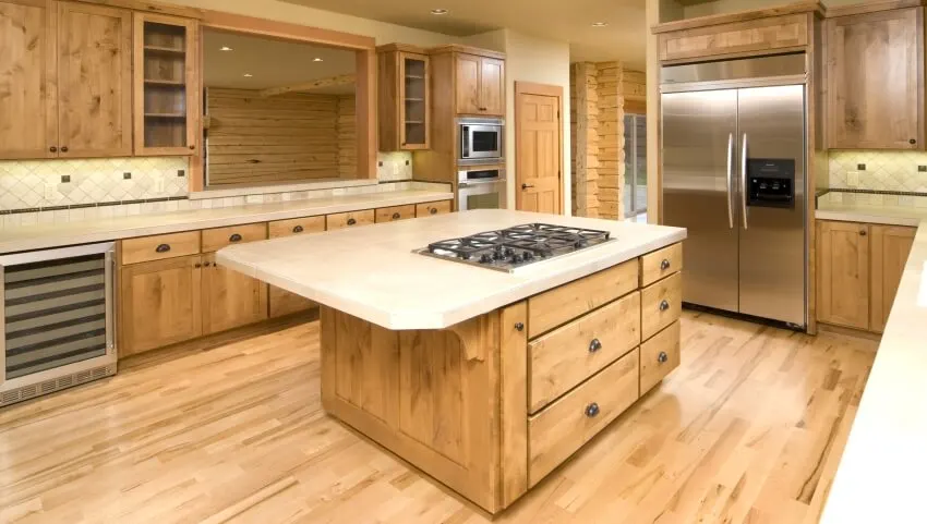 Empty kitchen with hardwood floor, birch cabinets, and an island with cooktop