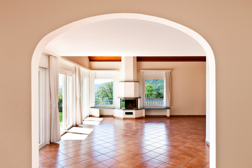 Empty room with tiles, fireplace and windows