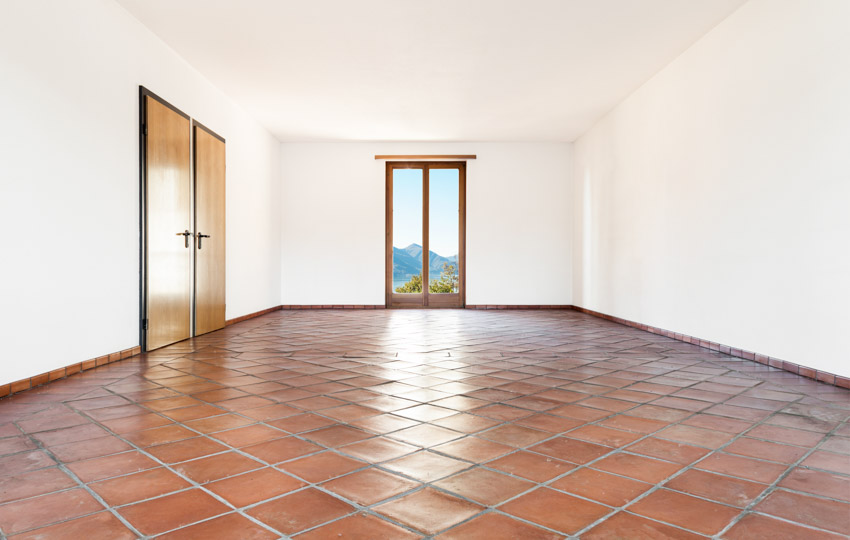 Empty room with white walls, doors, and Saltillo tile floors