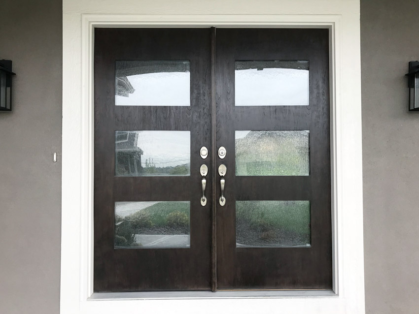 Front door with dark doosr, glass panels, handles, and white trim