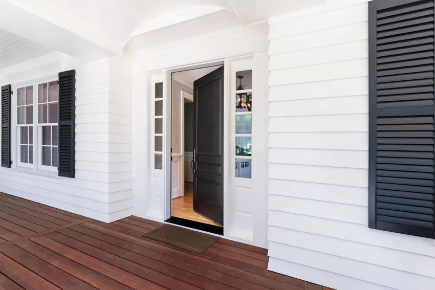 Front porch area with black painted door, and wood plank flooring