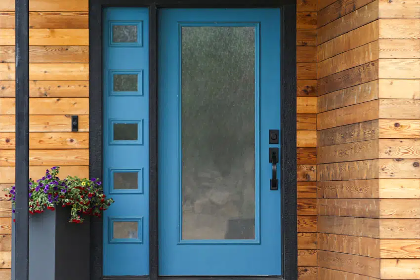 Front porch area with frosted glass front door and wood house siding