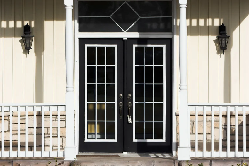 Porch with black double doors, trim, railings, and siding