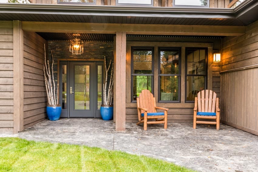 Front porch with chairs, wood siding, windows, and obscure glass front door