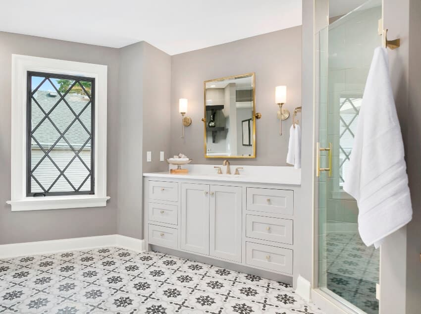 Gorgeous bathroom interior with beautiful patterned floor tiles, white counter with sink and film frosted glass shower doors