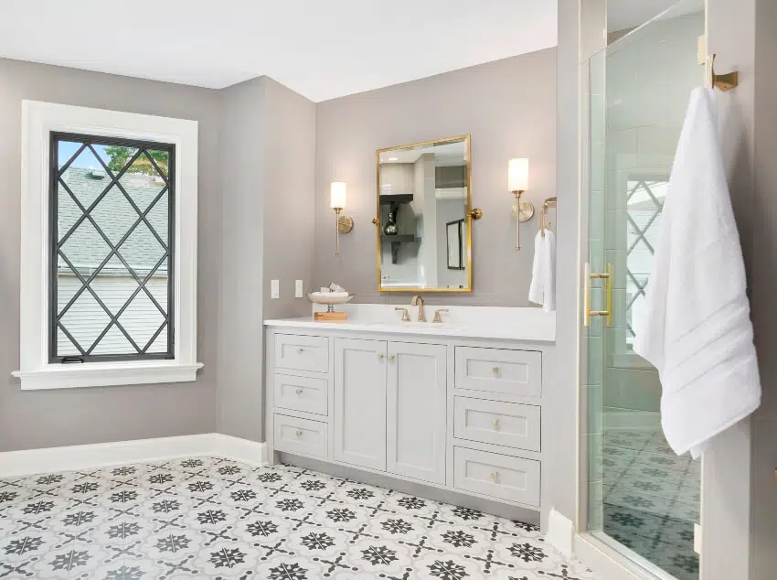 Patterned wall tiles, sink with faucet with gold finish, and mirror with gold frame