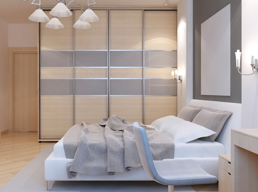 Gorgeous modern bedroom features large built in closet with sliding doors, white walls and light laminate