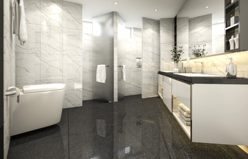 Granite flooring and marble tile wall in a large bathroom with vanity and a wall-mounted toilet