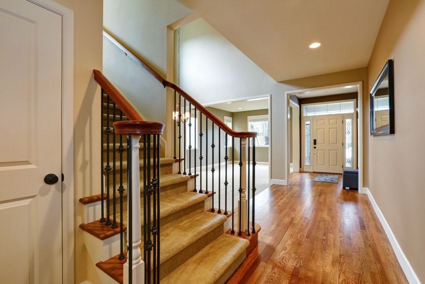 House entranceway with wood flooring, staircase, front door, ceiling light, and taupe walls