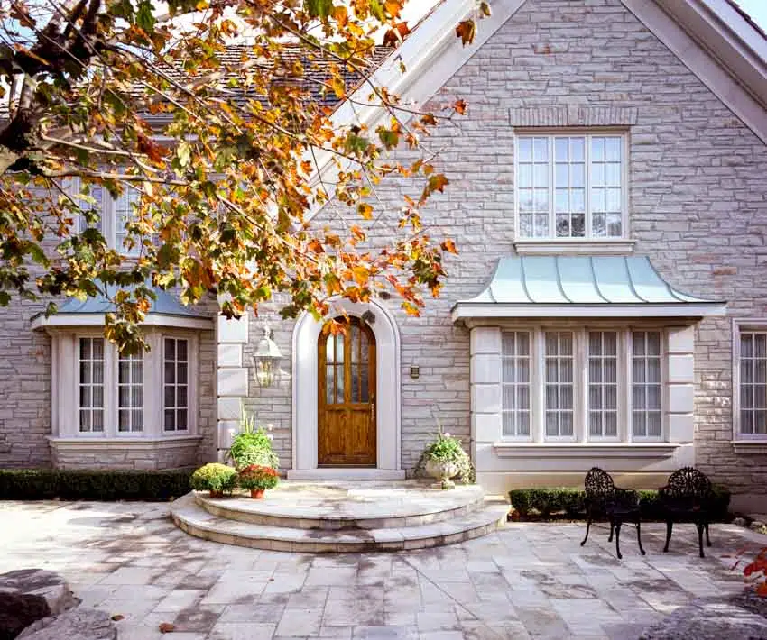 House exterior with frosted glass front door, windows, stone brick wall, and paved patio