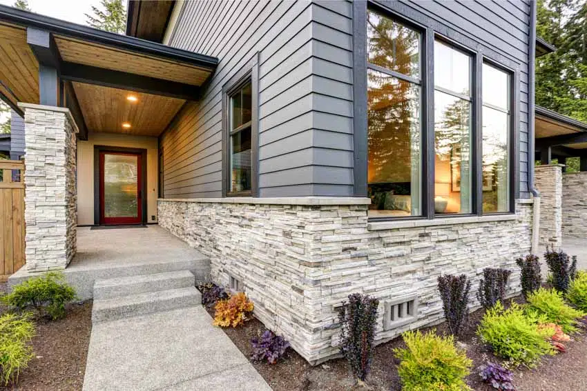 House exterior with stone wall cladding, house siding, windows, and frosted glass front door