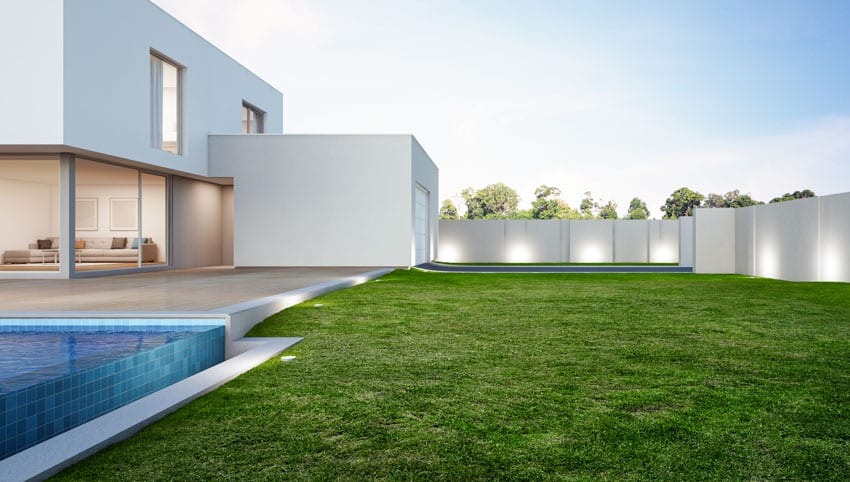 House exterior with white walls, lawn, and fence & patio illumination