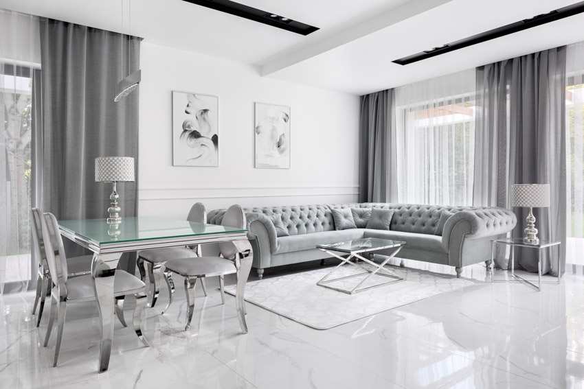 Room with tufted sectional, grey curtains and dining table with glass top