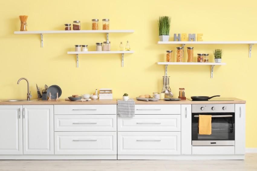 Interior of modern kitchen with yellow walls and shelving with brackets