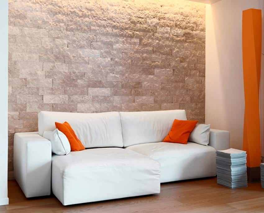 Interior view of a modern living room with fabric sofa, stone wall cladding and wood floor
