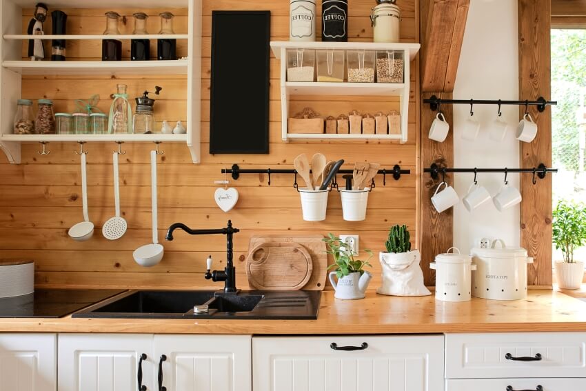 Kitchen in rustic style with vintage kitchen ware, wood backsplash, and white shelves and cabinets