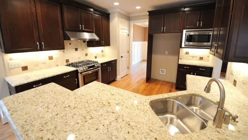 Kitchen interior with dark wooden cabinets and beige brown granite countertops