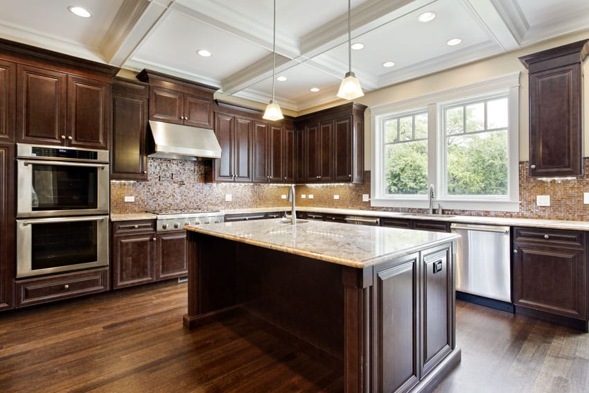 Kitchen with backsplash, cherry cabinets, island, wood floors, countertops, windows, pendant lights, oven, and range hood