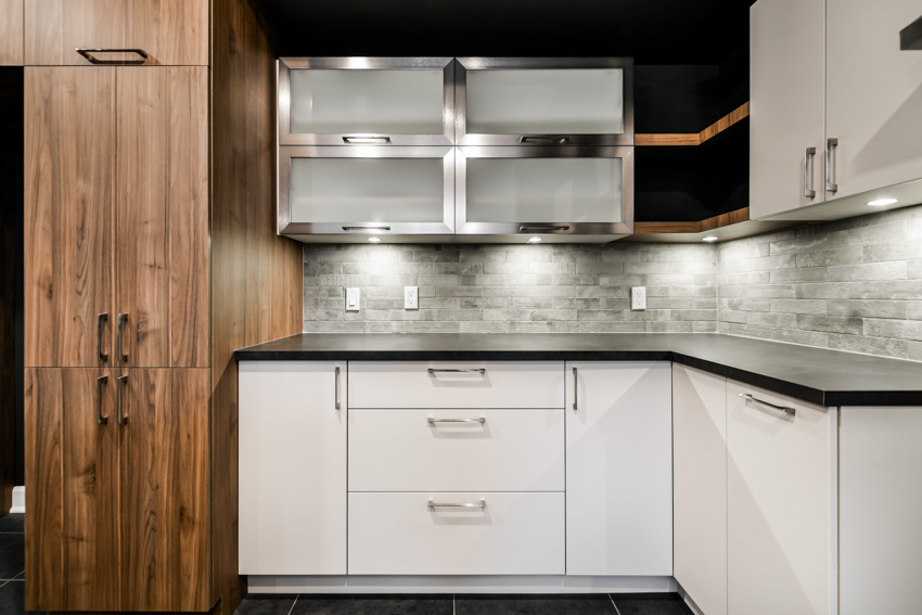 Kitchen with backsplash, frosted glass cabinets, countertops, drawers, and under cabinet lighting fixtures