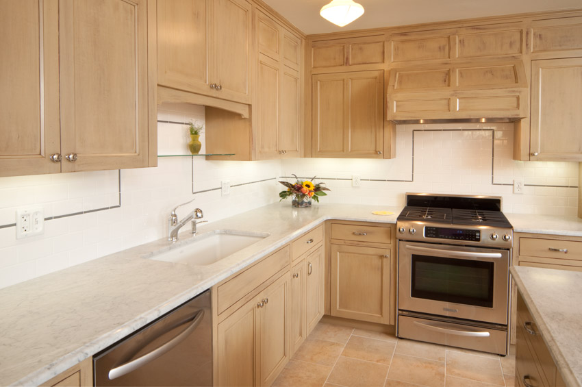 Kitchen with beech cabinet doors, countertop, sink, faucet, stove, oven, and backsplash