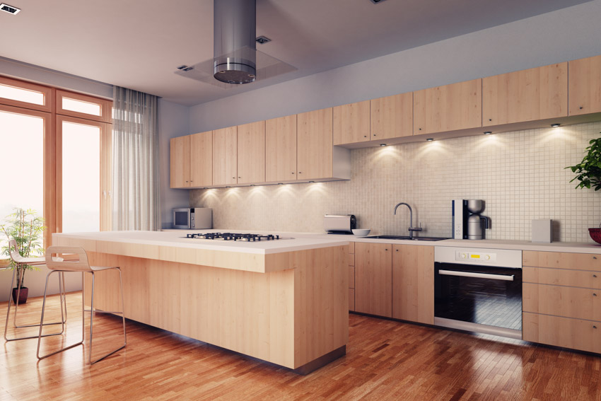 Kitchen with beech cabinets, wood floors, bar counter, stool, backsplash, windows, and range hood