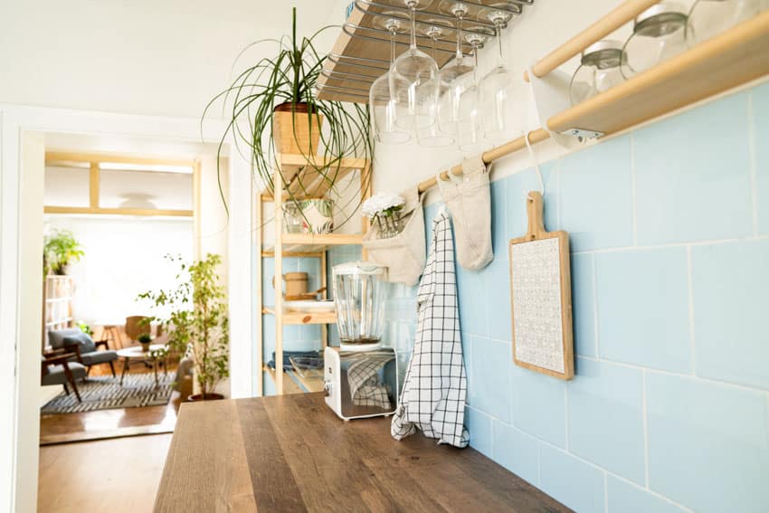 Kitchen with blue backsplash for cherry cabinets, wood countertop, and floating shelves