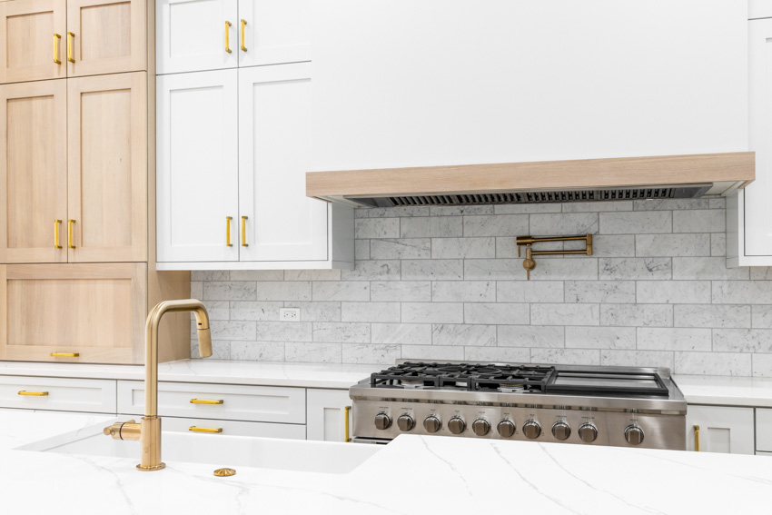 Kitchen with natural stone brick backsplash, cabinets, countertop, sink, and faucet