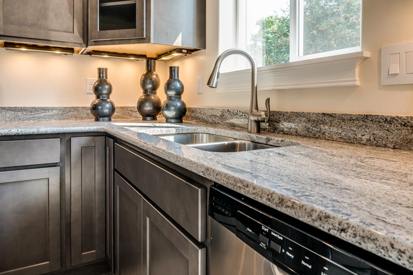 Kitchen with cabinets, sink, faucet, gray granite countertops, and window