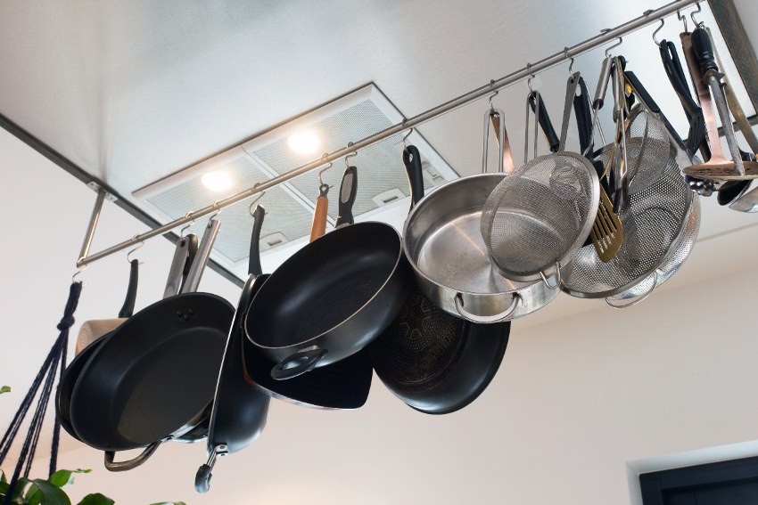 A kitchen with cookware hanging on ceiling mounted racks