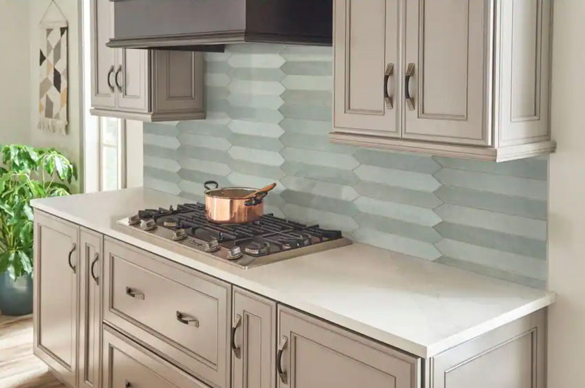 Kitchen with countertop, stove, cabinets, and picket subway tile backsplash