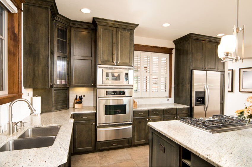 Kitchen with black cabinets, white windoes and travertine floors