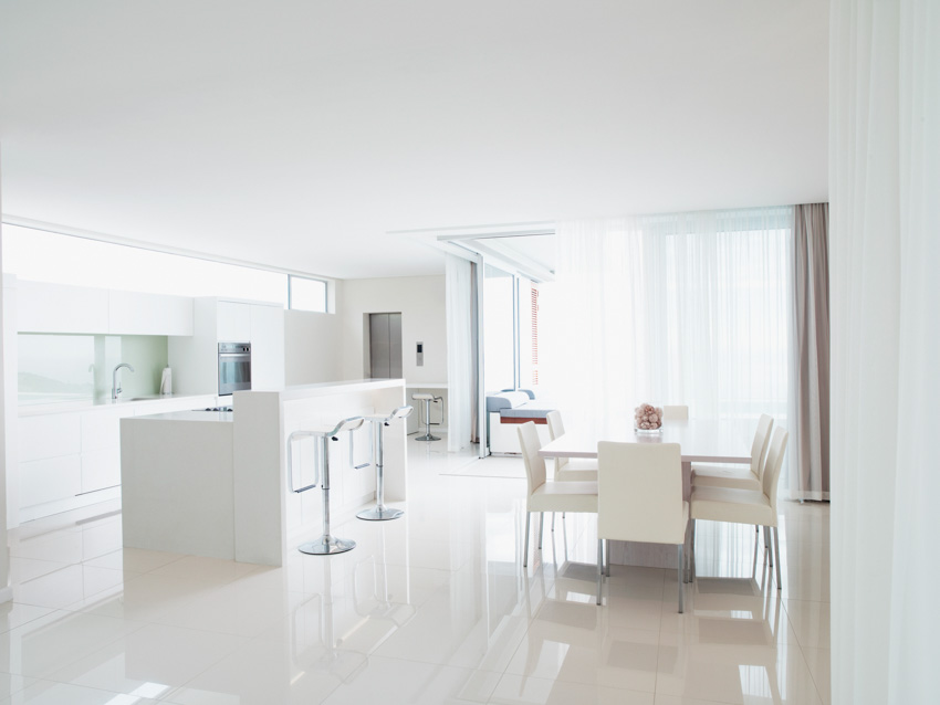 All-white kitchen with dining area, bar counter, stools and windows