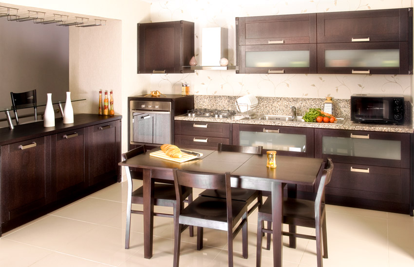 Kitchen with dining table, chairs, frosted glass cabinets, backsplash, range hood, and countertops