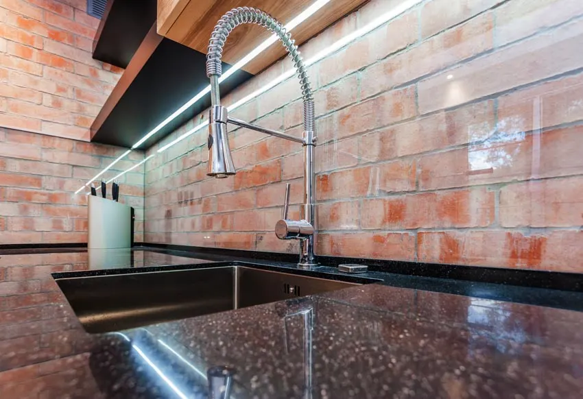 Kitchen with faux brick backsplash, countertop, sink, and faucet