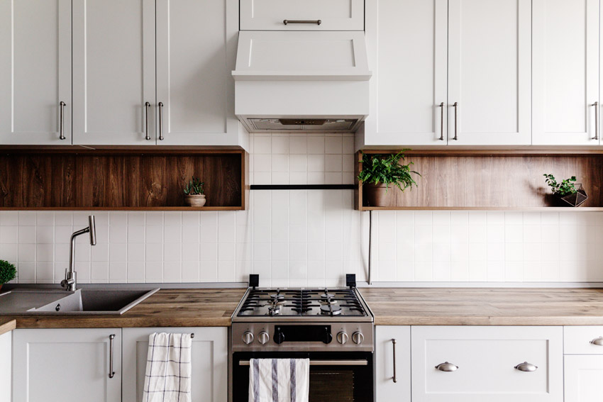 Kitchen with frameless recessed panel cabinets, backsplash, wood countertops, sink, faucet, and cabinets