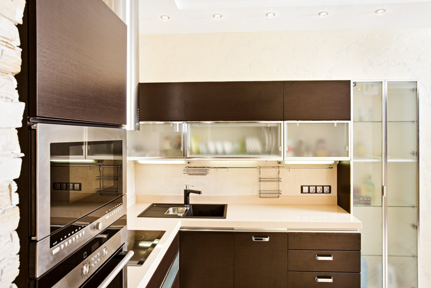 Kitchen with frosted glass cabinets, countertops, stove, sink, and faucet