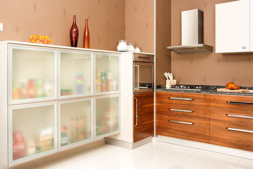 Kitchen with frosted glass cabinets, drawers, range hood, countertops, and stove