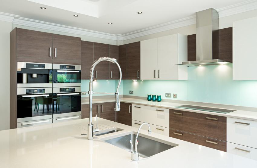 Kitchen with glass backsplash, countertops, sink, faucet, melamine cabinets, faucet, sink, stove, and range hood