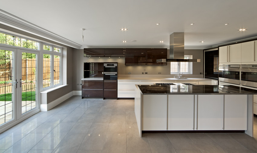 Kitchen with glazed porcelain wood look floor tile, island, range hood, glass door, backsplash, countertop, and cabinets