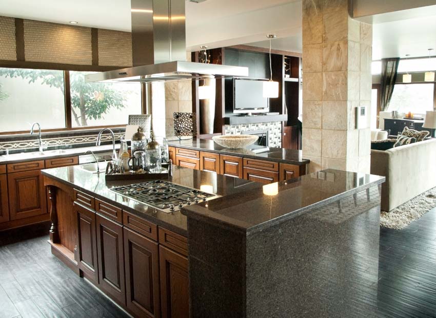 Kitchen with graphite granite countertop, range hood, stove, cabinets, and windows