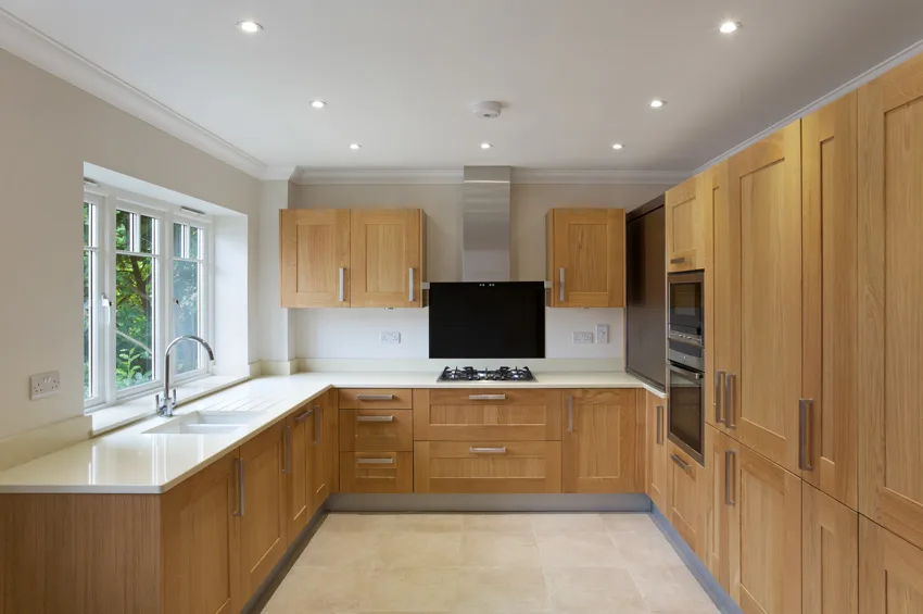 Kitchen with hardware for oak cabinets, backsplash, stove, range hood, ceiling lights, and windows