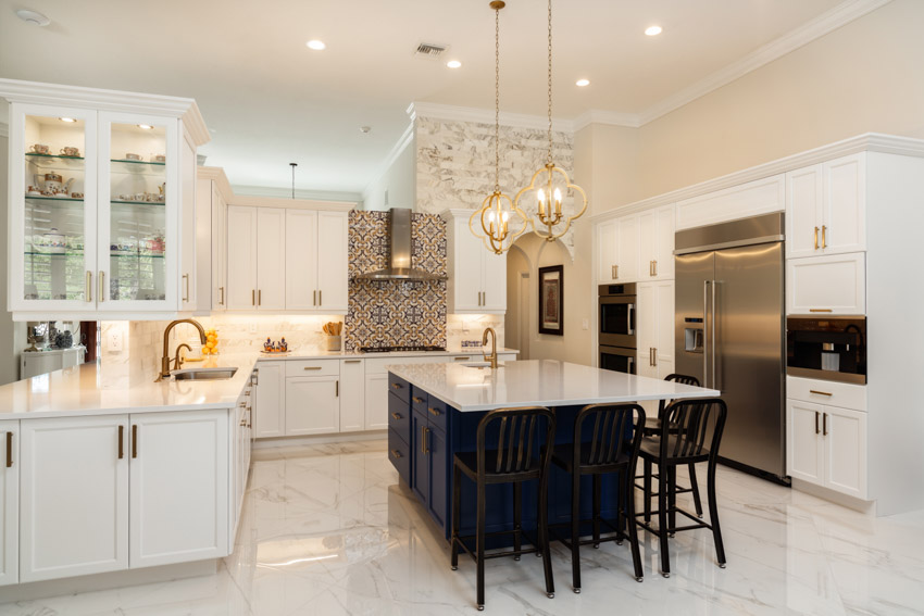 Kitchen with island, chairs, pendant lights, cabinets, backsplash, range hood, glazed porcelain tile floor, and refrigerator