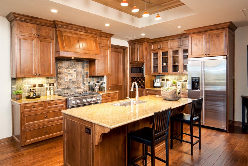 Kitchen with island, countertop, chairs, backsplash, natural wood cabinets, ceiling lights, and wooden floors