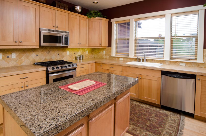 Kitchen with island, countertops, beech cabinets, backsplash, windows, and dishwasher
