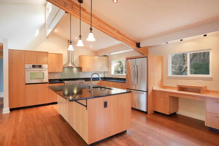 Kitchen with island, countertops, beech cabinets, pendant lights, windows, refrigerator, and wood flooring