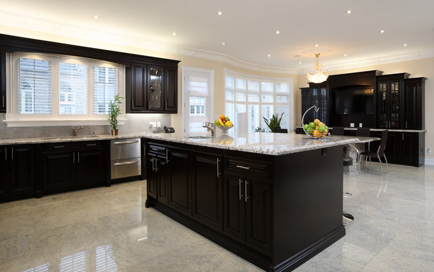 Kitchen with black island, granite countertops, windows and cabinets