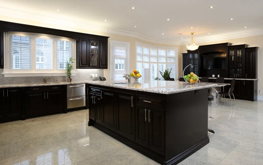 Kitchen with island, countertops, glazed porcelain tile floor, windows, and cabinets