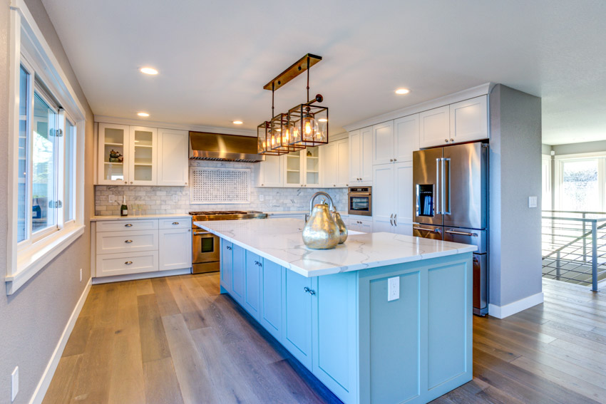 Kitchen with island, countertops, porcelain backsplash, wood flooring, pendant light, window, refrigerator, and cabinets