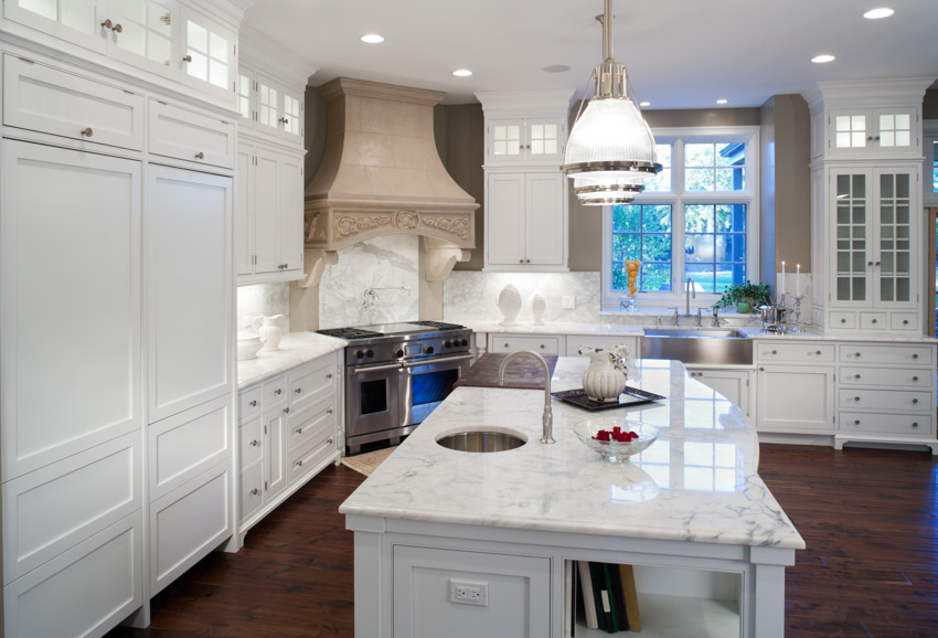 Kitchen with island, wood floors, countertops, white cabinets, pendant light, porcelain backsplash, and windows