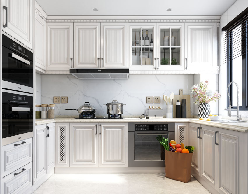 Kitchen with large glazed porcelain tile backsplash, countertops, cabinets, stove, and window